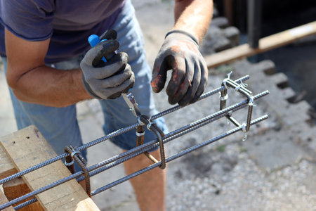 Worker at the construction site using a screwdriver to tighten the steel frameの写真素材