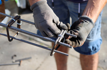 Worker welds a steel structure at a construction site. Professional builder works with reinforcement steel.  Construction work in process.の写真素材