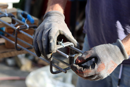 Worker hands in protective gloves holding a metal bar on construction siteの写真素材