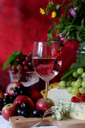 Wine, cheese, grapes and fruits on a red background.の写真素材