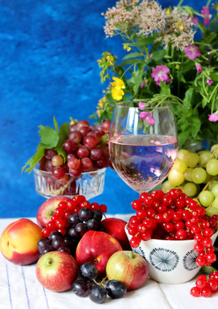 Wine and fruit on a table. Beautiful composition of juicy berries, grapes and rose wine. Harvest celebration. Textured background with copy space.の写真素材