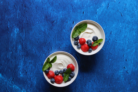 Tasty yogurt with berries in bowls on color background, top viewの写真素材