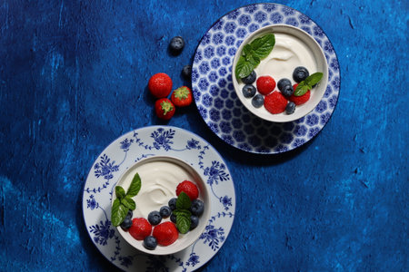 Greek yogurt with fresh berries and mint on blue background. Top viewの写真素材