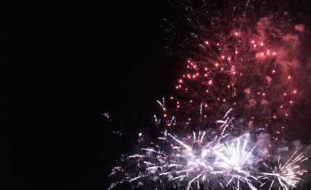Colorful fireworks of various colors over night sky background, celebration concept
