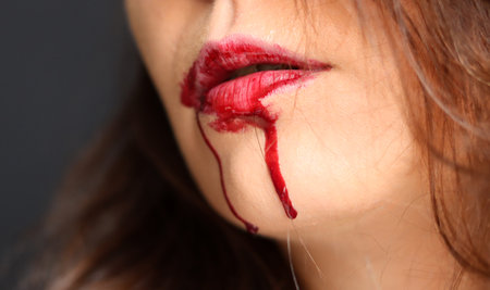 Young woman with bloody lips on dark background, closeup. Halloween conceptの写真素材