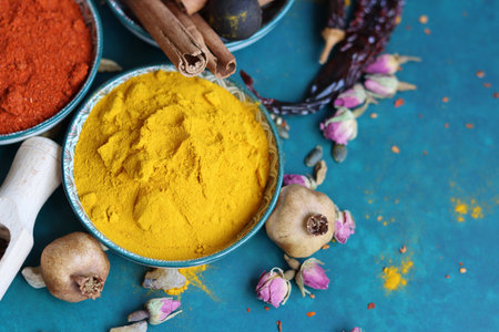 Turmeric powder in bowl and spices on turquoise background.の写真素材