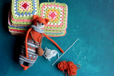 Cute Amigurumi Fox toy. Knitted fox toy with wool yarn and crochet hook on a turquoise background with copy space.の写真素材