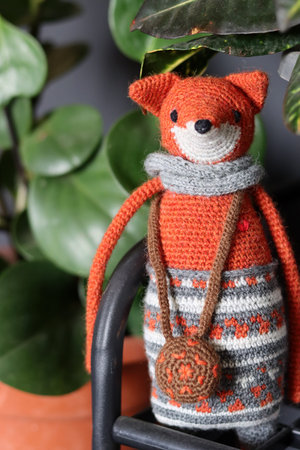 Handmade crochet doll with green plant in the background, stock photoの写真素材