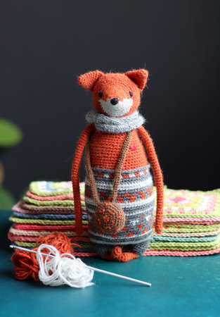 Knitted toy  with yarn and knitting needles on a dark background