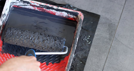 Worker paints the wall with a paint roller, close-upの写真素材