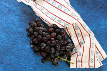 Bunch of black grapes on a napkin on a blue backgroundの写真素材