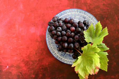 Grapes in a plate on a red background, top viewの写真素材