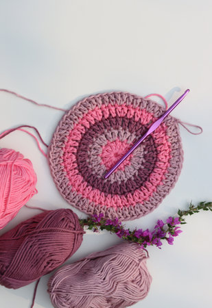Crocheted round element top view. Organic pink cotton yarn on white background with copy space. Hobbies and leisure concept.の写真素材