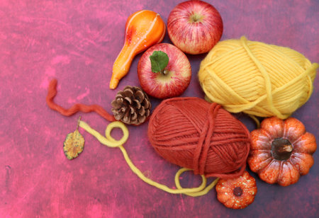 Autumn still life with pumpkins, apples and yarn on red backgroundの写真素材