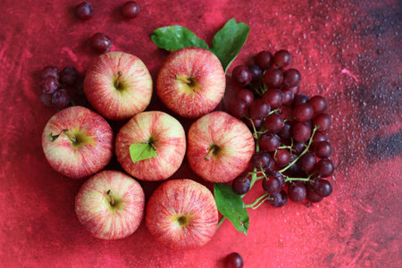 Red apples and grapes on a red background. Top view, flat layの写真素材