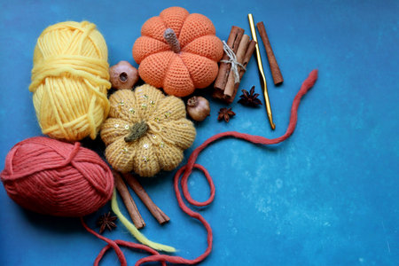 Crochet pumpkin made of cotton on vibrant blue background. Amigurumi toy close up. Handmade autumn decoration.の写真素材