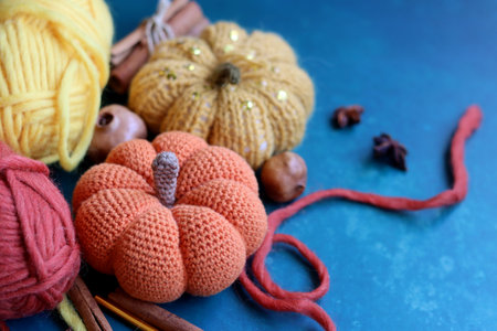 Handmade knitted pumpkin with woolen threads and knitting needles on blue backgroundの写真素材