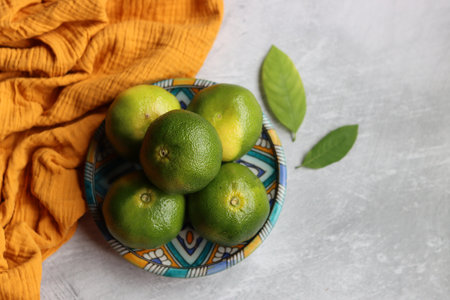 Bowl with fresh ripe limes and napkin on light backgroundの写真素材