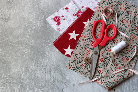Sewing accessories: scissors, thread, fabric on a gray background