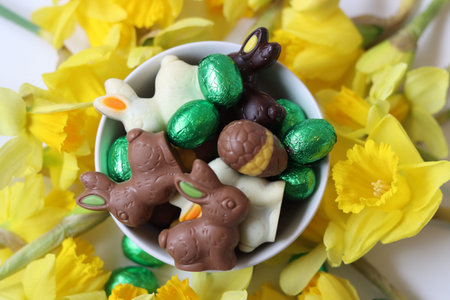 Chocolate Easter bunny and eggs with yellow daffodils.