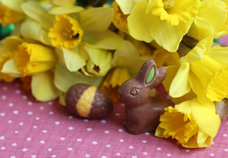 Easter chocolate bunny and daffodils on a pink tablecloth
