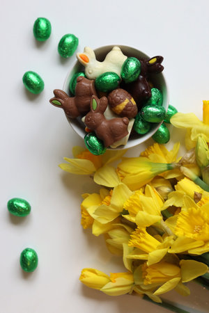 Chocolate Easter bunny and daffodils on a white backgroundの写真素材