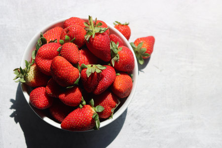 Strawberries in a bowl on a light background, top viewの写真素材