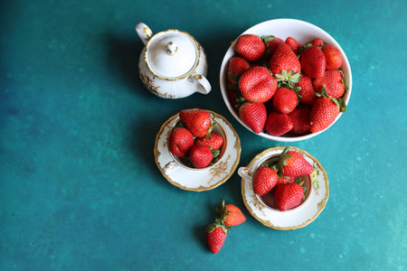 Strawberries in cup and teapot on turquoise backgroundの写真素材