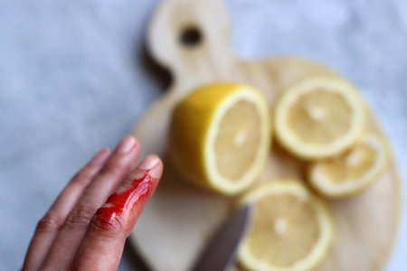 Woman accidentally cuts her finger. Real blood on woman's hand. Female hands cut lemons on a wooden...