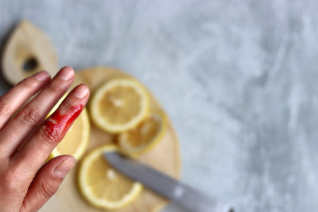 Woman's hand holding a slice of lemon on a cutting board.