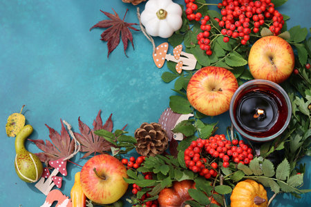 Autumn composition with pumpkins, apples and berries on blue background
