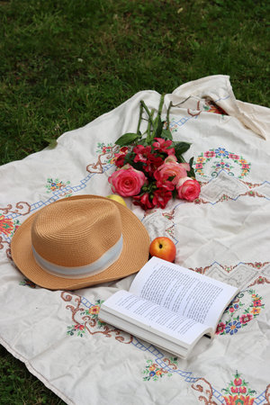 Bouquet of flowers, hat and book on a picnic blanket