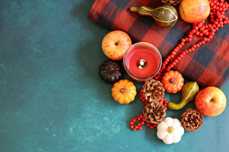 Pumpkin, apples, red beads and candle on a blue backgroundの写真素材