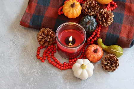 Autumn still life with burning candle, pumpkins, red beads and plaidの写真素材