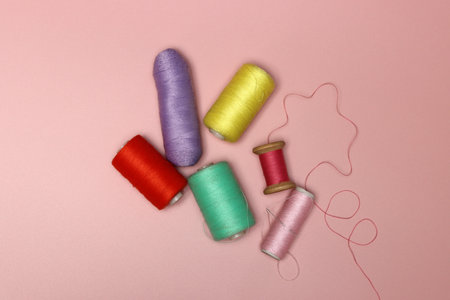Spools of multicolored thread and buttons on a pink backgroundの写真素材