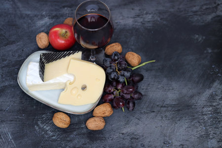Cheese plate with grapes, nuts and red wine on dark backgroundの写真素材
