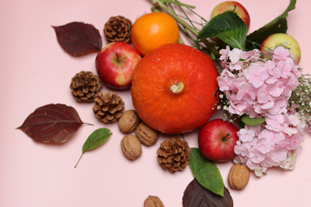 Autumn still life with pumpkins, apples, berries and leaves on pink backgroundの写真素材