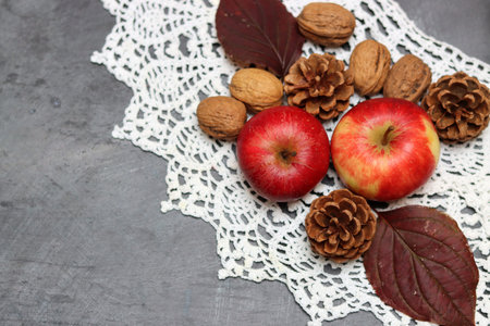 Apples, walnuts and autumn leaves on a gray background.の写真素材