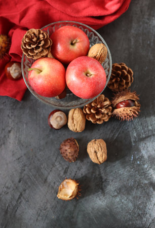 Autumn still life with apples, chestnuts and pine cones on dark background with space for text.の写真素材
