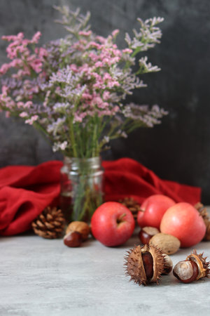 Autumn still life with apples, nuts and flowers on gray backgroundの写真素材