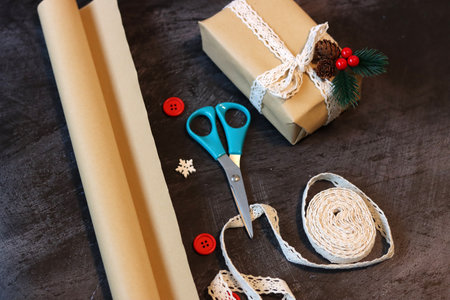 Wrapping christmas presents in craft paper with ribbons and scissorsの写真素材