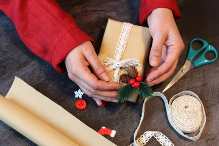 Female hands wrapping christmas gifts on a wooden table. Preparing for Christmas.