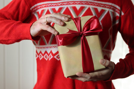 Hands of a man in a red sweater holding a gift boxの写真素材