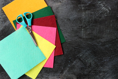 Felt fabric of different colors and scissors on dark background with copy space. Crafts and hobby concept.の写真素材