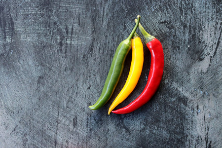 Red, yellow and green chilli peppers on a black background.の写真素材