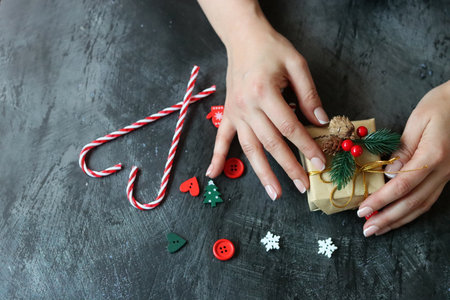 Female hands with beautiful manicure holding christmas gift on dark backgroundの写真素材