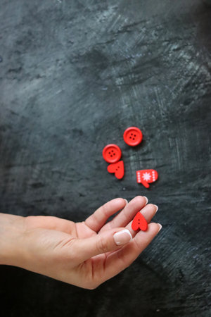 Female hand with red hearts and buttons on a black background. Valentine's day conceptの写真素材