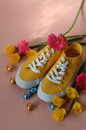 Yellow sneakers with a bouquet of flowers on a pink background.