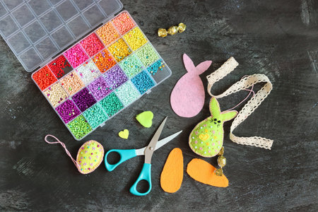 Easter bunny, eggs, beads and scissors on a black background