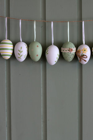 Easter eggs hanging on a rope on a green wooden wall.の写真素材